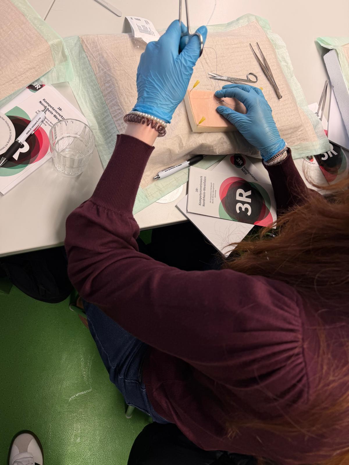 Eine Schülerin übt auf einem künstlichen Hautpad das Nahttechniken.