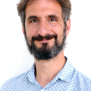 Bild von C. Barkus, Mann, mittleres Alter mit schwarzen Haaren und Bart und hellblau gepunkteten Hemd.