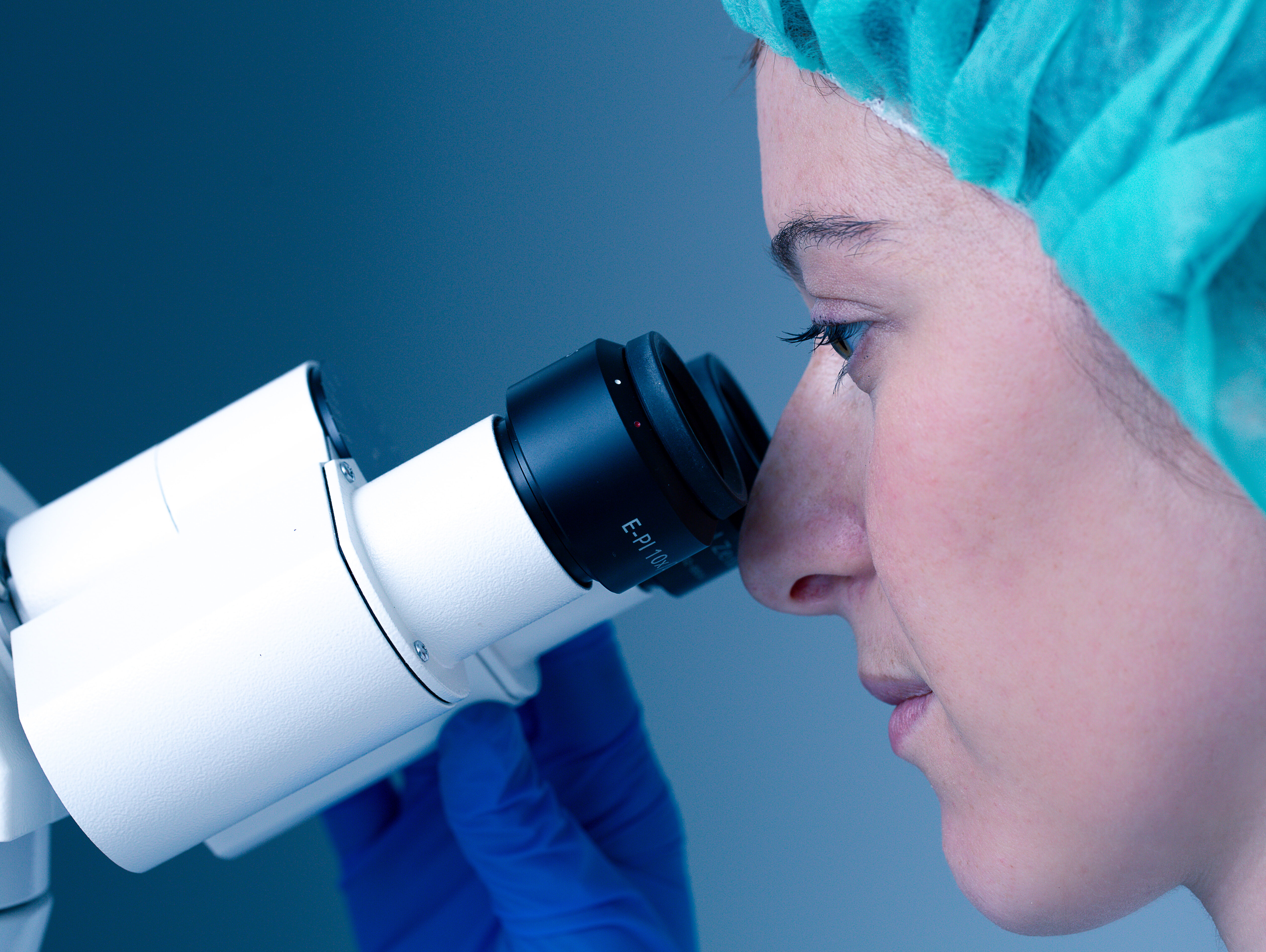 Eine Forscherin schaut durch das Mikroskop