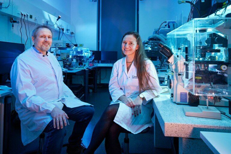 Prof. Volker Busskamp und Prof. Elvira Mass sitzen in einem Labor.