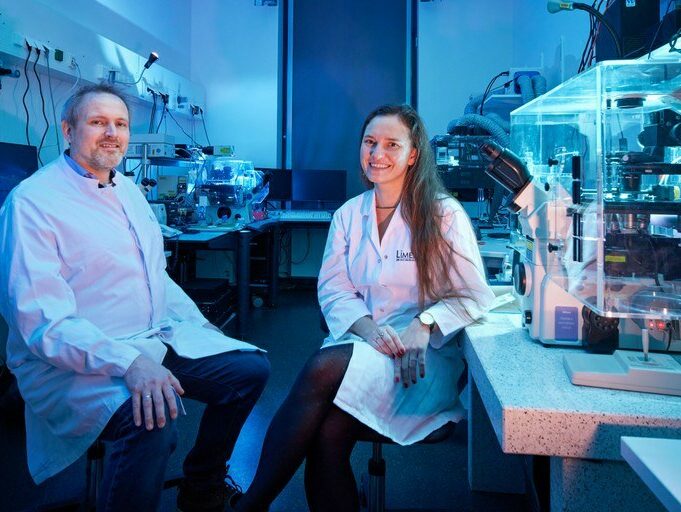 Prof. Volker Busskamp und Prof. Elvira Mass sitzen in einem Labor.